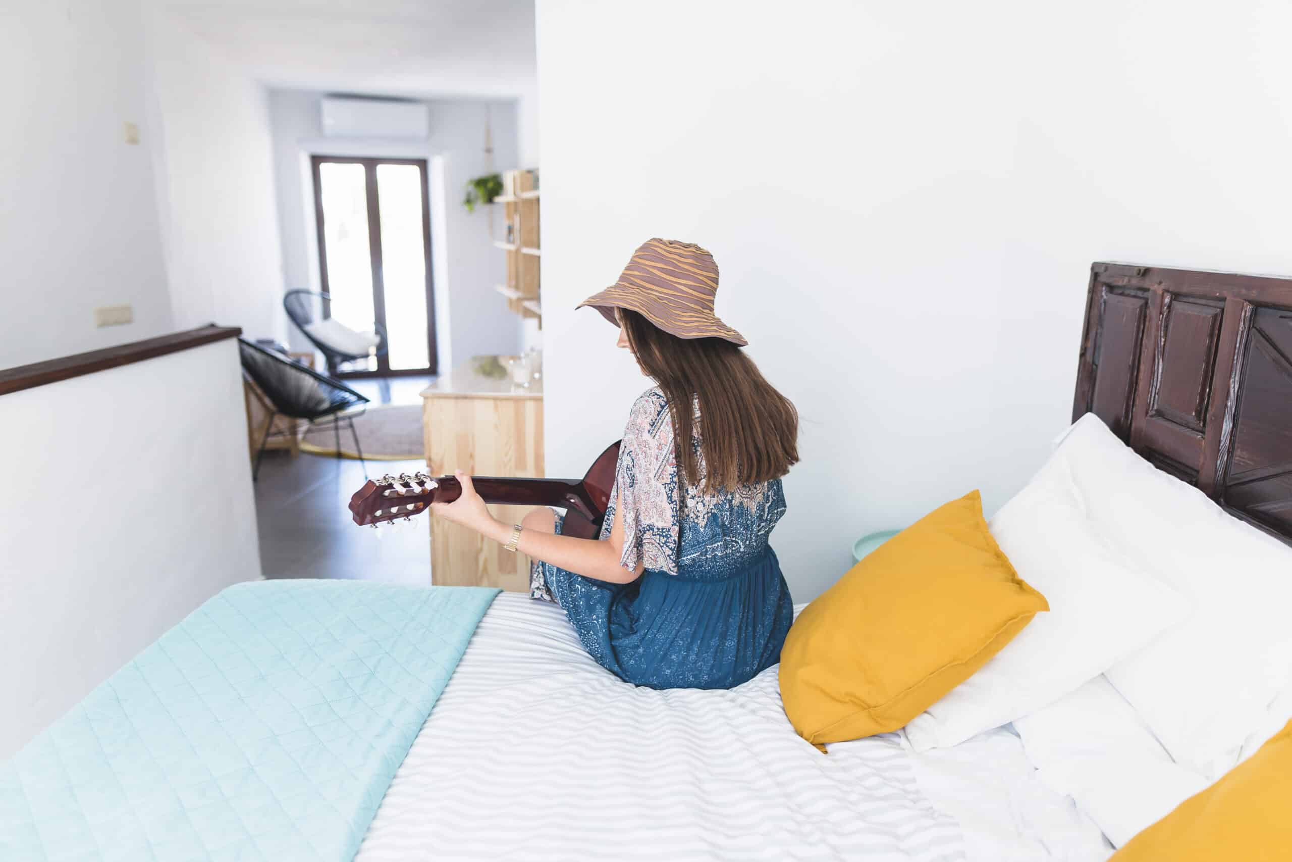 rear view woman sitting bed playing guitar scaled
